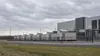 A generic modern data center with enclosed generator units behind a low fence under an overcast sky.