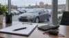 Unbranded used car seen beyond blank financing forms, calculator and keys on a dealership desk