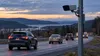 A roadside license-plate camera overlooks traffic on a generic New York highway at dusk.