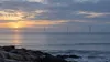Distant offshore wind turbines on a calm Atlantic horizon under a muted dawn sky