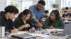 Young adults work with an instructor during a hands-on workforce training session in a bright New York community classroom.