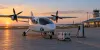 An illustrative electric aircraft charges beside secured medical cargo at a coastal North Carolina regional airport.