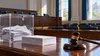 Illustrative empty civic hearing room with a secure ballot box, blank ballots and a judge's gavel.