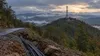 Cell tower above a repaired mountain road and exposed communications conduit in western North Carolina.