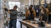 Adult learners watch an instructor demonstrate equipment in a community college skilled-trades laboratory.