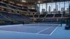 Empty indoor blue tennis court prepared inside a modern arena with tiered seating