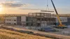 Modern public hospital under construction on the North Dakota prairie with a crane lifting a final steel beam.