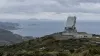 Coastal air-defense radar installation overlooking the sea under an overcast sky.