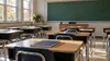 Empty Ohio public-school classroom with desks, notebooks and pencils in morning light.