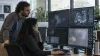 Two AI safety researchers review model activity on monitors in an unbranded operations room.