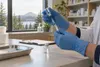 Gloved hands prepare an unbranded vaccine dose at a pharmacy counter with an Oregon landscape beyond the window.