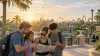 A family reviews a map and phone at sunrise with generic Central Florida amusement rides in the distance.