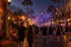 Generic Central Florida theme park boulevard at night with autumn lighting, palm trees and visitors