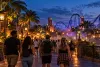 AI-generated editorial image of adult visitors walking through a generic Central Florida theme park at twilight.