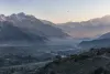 Mountainous Afghanistan-Pakistan border region at dawn with a distant aircraft
