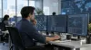 Cybersecurity analyst reviewing network activity across multiple monitors in a modern operations center