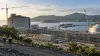 A generic coastal LNG construction site with industrial modules, cranes and tropical hills