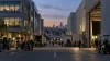 Film crews work between anonymous studio buildings on a Los Angeles backlot at dusk.