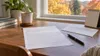 Blank registration form, envelope, pen and calendar on a desk beside autumn foliage