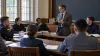 A civilian professor leads a seminar with cadets in a military academy classroom