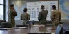 Military planning professionals review an organizational structure in a conference room.