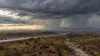 Heavy rain falls from a large storm over a desert city and interstate in the U.S. Southwest.