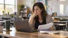 Teacher reviewing financial paperwork beside a laptop in an empty classroom after school