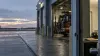 Airport fire station beside a runway at dawn, with a fire engine in an open bay and a helmet beside a document folder