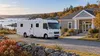 Unbranded mobile medical clinic beside a small coastal New England health building in autumn