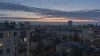 A generic Eastern European residential skyline before dawn under a muted sky.