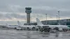 Unbranded passenger aircraft parked beside an airport control tower under overcast skies