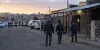 Police investigators approach a cordoned neighborhood venue in South Africa at dawn.