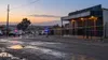 Police vehicles stand behind a cordon outside a closed township venue at dawn.