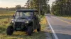 Unbranded utility terrain vehicle parked beside a rural South Carolina road bordered by pine trees and farmland