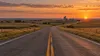 Open prairie highway and distant farm silos in South Dakota at dusk, illustrating statewide economic choices.