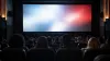 A full, unbranded movie theater audience watches an abstract illuminated cinema screen.