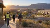 Workers walk toward a commercial and light-industrial district in the New Mexico high desert at sunrise.