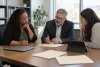 University administrators review blank compliance materials in a naturally lit campus office.