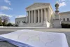 The United States Supreme Court building with out-of-focus congressional district maps in the foreground.