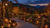 Illustrative autumn amusement park path lined with glowing pumpkins in the Smoky Mountain foothills at dusk