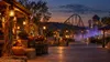 A generic Texas amusement-park midway at twilight with pumpkins, autumn lanterns, a distant roller coaster and theatrical fog
