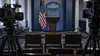 Three empty chairs behind a velvet barrier in a symbolic White House press briefing room
