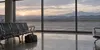 An empty regional airport departure hall overlooking a quiet runway at dawn
