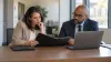 Two education compliance administrators review policy procedures at a conference table.