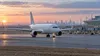 An unbranded passenger jet taxis beside an airport terminal at dawn