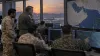 Allied military officers review radar displays in a Gulf-region operations room at dusk.