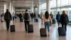 International travelers walking through a modern U.S. airport arrivals hall in soft natural daylight