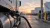 An unbranded freight truck refueling with diesel at an industrial terminal at dawn.