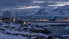 Symbolic Arctic airfield in Greenland with a radar installation, transport aircraft, snow-covered mountains and icy coastal water at blue hour