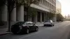 Unbranded conventional sedan and autonomous test vehicle on a quiet city street in natural morning light